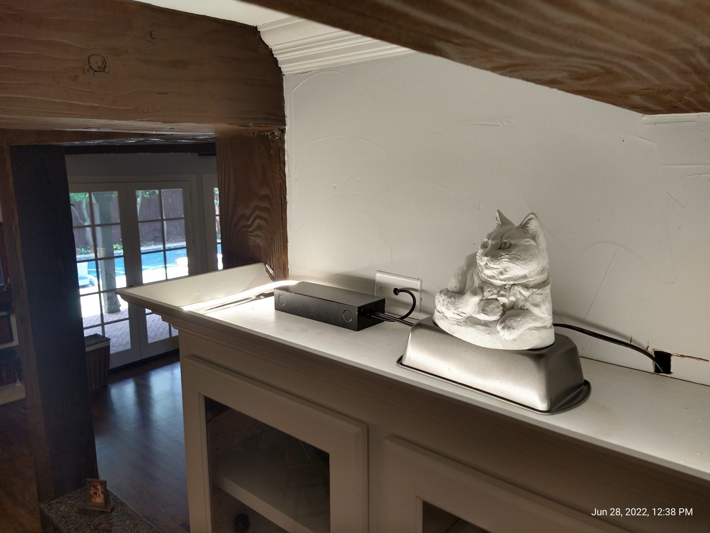 Built-in mantel with an exposed beam and crown molding, opening to a poolside sunroom